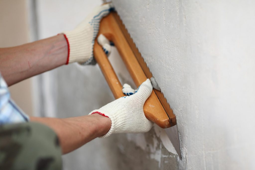 man flattening the wall with plaster