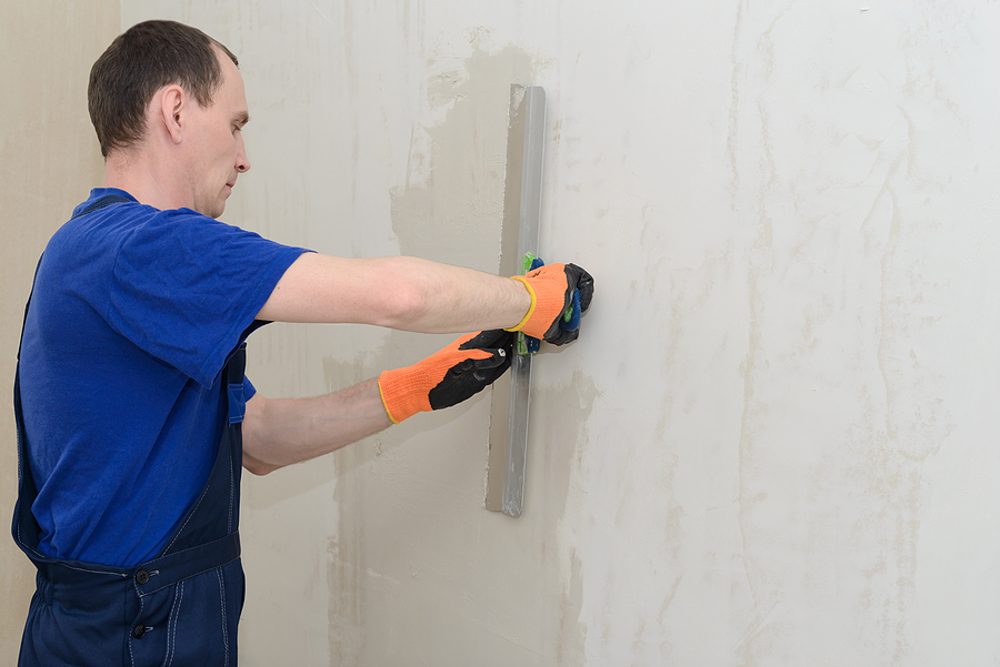 man wearing his working clothes applying plasters o the wall