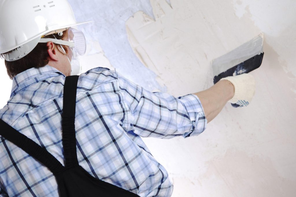man wearing a safety helmet while plastering the wall